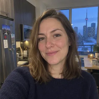 Portrait of Kayla Moffatt, a woman in her thirties with shoulder length hair and a navy sweater
